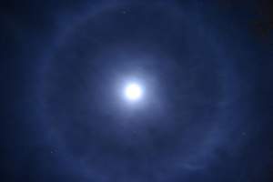 C. Halo: Ring around the moon. This optical phenomenon is caused by light refracting through tiny ice crystals. It most commonly occurs when light passes through thin, icy, high-altitude clouds, but can also occur with such clouds near ground level in winter months. It appears as rings, spots, and pillars. 
